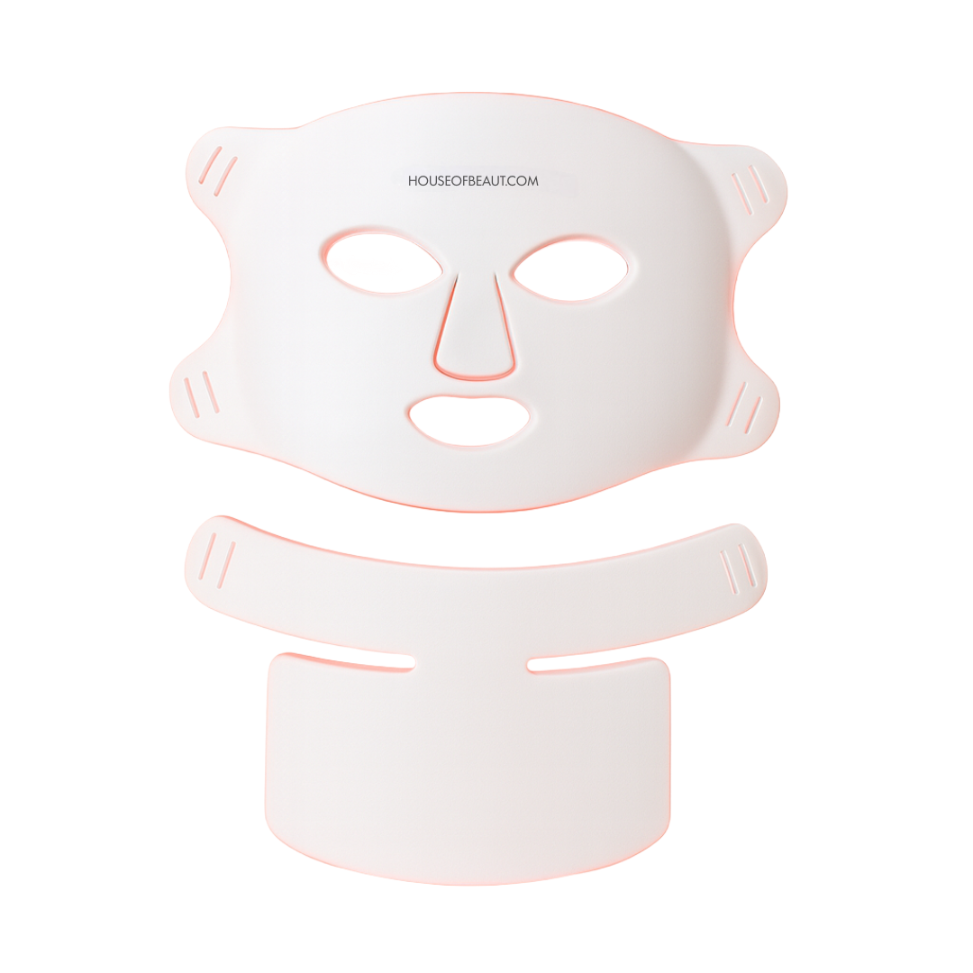 White face mask with pink accents on a white background, featuring 'HOUSEOFBEAUT.COM' branding.